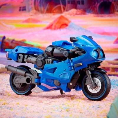 Motociclo de brinquedo azul em areia colorida com fundo desfocado