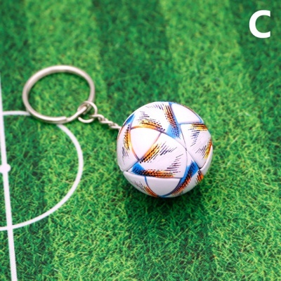 Porta-chaves com bola de futebol decorada sobre campo de futebol em miniatura