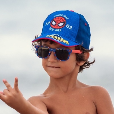 Criança de óculos de sol e boné do Homem-Aranha ao ar livre