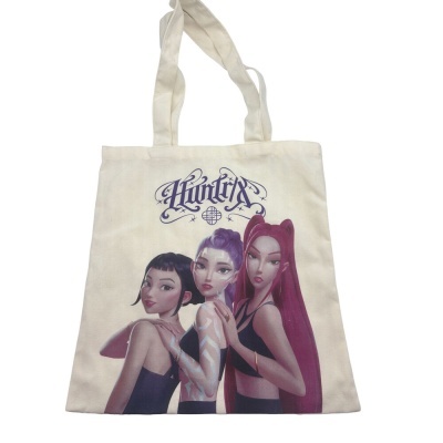 Tote bag bege com ilustração de três mulheres e texto Huntrix