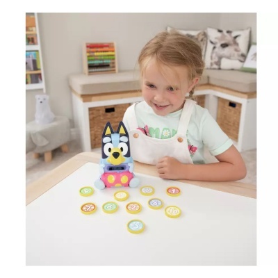 Menina a brincar com brinquedo de cão azul e branco e círculos numerados numa mesa branca