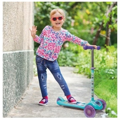 Criança com trotinete azul turquesa e roupa colorida ao ar livre