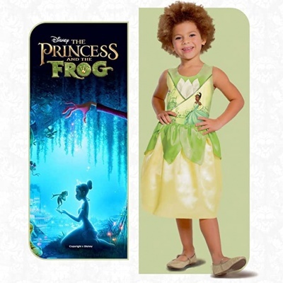 Criança com vestido amarelo e verde inspirado na Disney The Princess and the Frog ao lado da capa do filme