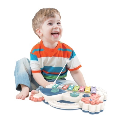 Criança com camisola às riscas coloridas a brincar com brinquedo musical colorido