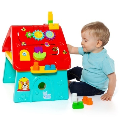 Brinquedo educativo em forma de casa colorida para crianças com peças interativas e criança a brincar