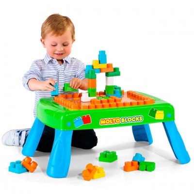 Criança brincando com mesa de blocos de construção coloridos