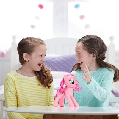 Duas meninas sorrindo com um brinquedo de pônei cor-de-rosa numa mesa