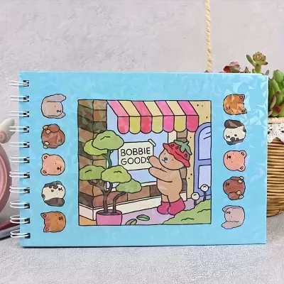 Caderno espiral azul com ilustração de personagem e loja com toldo colorido e inscrições BOBBIE GOODS