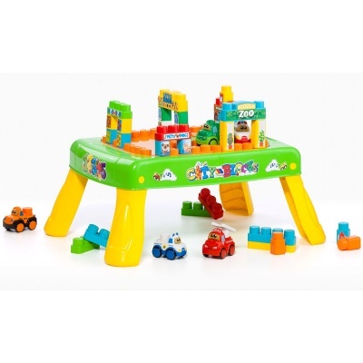 Mesa de brincadeiras verde e amarela com blocos e carros pequenos coloridos