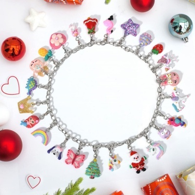 Pulseira com pendentes coloridos variados sobre fundo branco com enfeites natalícios