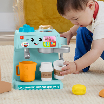 Brinquedo máquina de café azul com chávenas e copo medidor em tapete bege com criança a brincar
