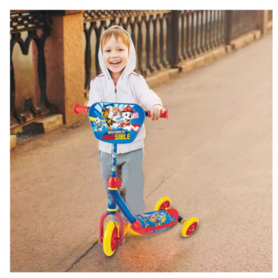 Criança a andar num trotinete colorido da Patrulha Pata num passeio com grade ao lado