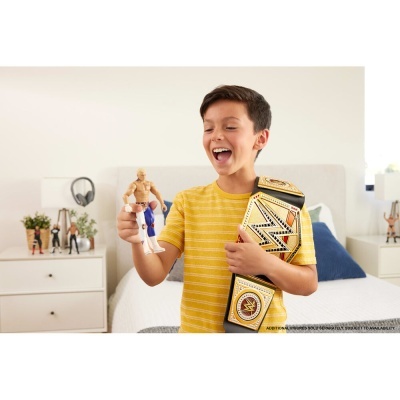 Menino a brincar com figura de ação de lutador e cinto WWE numa cama.