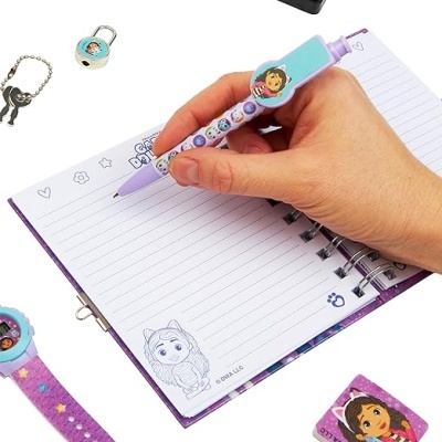 mão a escrever em caderno pautado com caneta decorada e acessórios temáticos de personagens animados