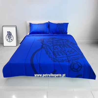 Conjunto de cama azul com padrão escuro e dois travesseiros, em quarto minimalista com chão branco