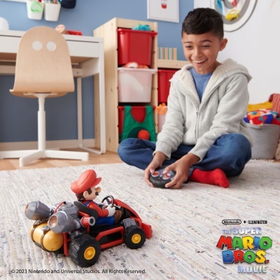 Figura de ação do Mario a conduzir um kart num tapete com criança a jogar