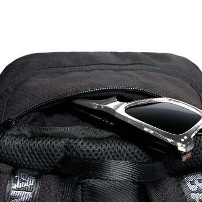 mochila preta com óculos de sol prateados e lentes escuras no bolso frontal aberto