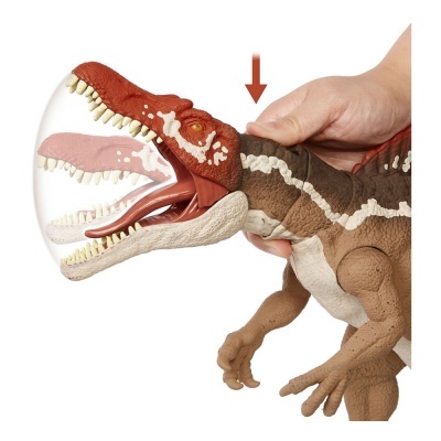 Brinquedo dinossauro Tiranossauro Rex castanho, vermelho e branco com boca aberta e mão humana