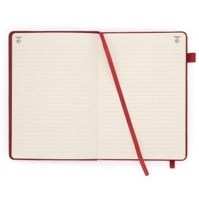 Caderno aberto com capa vermelha e páginas pautadas creme com marcador vermelho