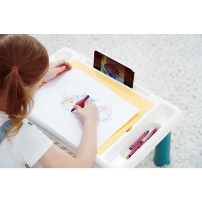 Criança a desenhar numa mesa infantil com suporte para telemóvel
