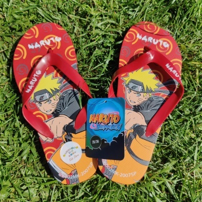 Sandálias vermelhas de dedo com estampa do Naruto sobre relva verde