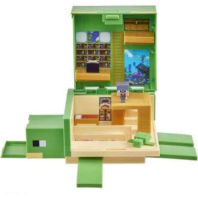 Caixa de brinquedo verde em forma de tartaruga com interior decorado como sala de estar e boneco pixelado