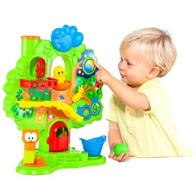 Brinquedo educativo colorido em forma de árvore com peças coloridas e criança loira a jogar