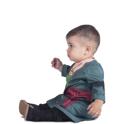 Bebé sentado com roupa de fantasia verde e calçado preto