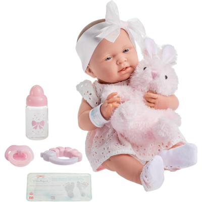 Boneca realista com vestido branco e laço, segurando coelho de pelúcia rosa e acessórios infantis