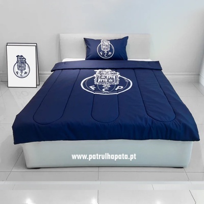 Cama com edredão e fronha azuis com emblema do FC Porto, quadro com emblema encostado à parede, piso azulejado branco
