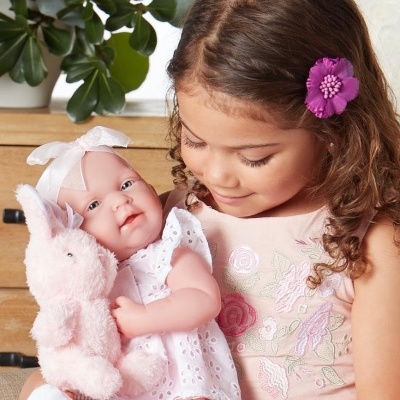 Menina a segurar boneca e coelho de pelúcia