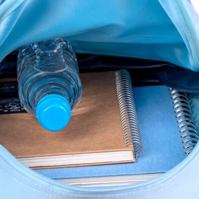 Interior de mochila azul com garrafa de água e dois cadernos espirais