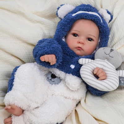 Bebé de brinquedo com fato felpudo azul e branco e urso de peluche cinzento às riscas