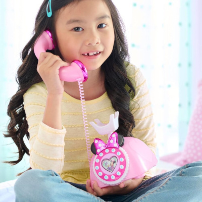 Menina com cabelo longo a segurar telefone de brinquedo cor-de-rosa com tema Minnie Mouse