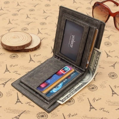 Carteira cinza aberta com cartões e dinheiro sobre superfície com padrão Paris e óculos ao lado