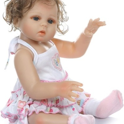 Boneca de bebé com vestido branco e meias rosa sentada