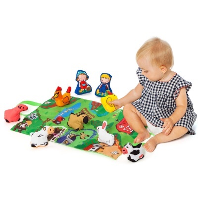 Criança a brincar com tapete e animais de tecido coloridos.