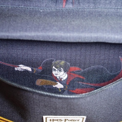 Mochila cinza com estampa de personagem de Harry Potter e etiqueta com texto