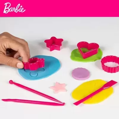 Ferramentas e massas de modelar coloridas sobre superfície branca com logo Barbie