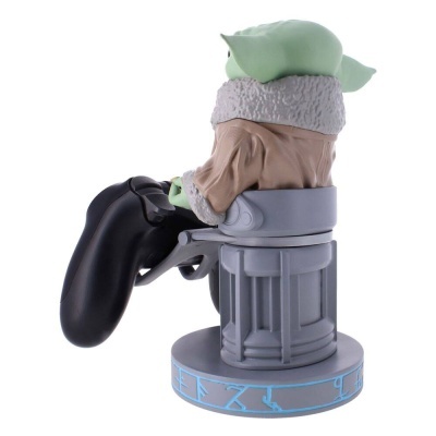 Figura Baby Yoda com casaco castanho sentada em trono cinza segurando comando de videojogos preto.