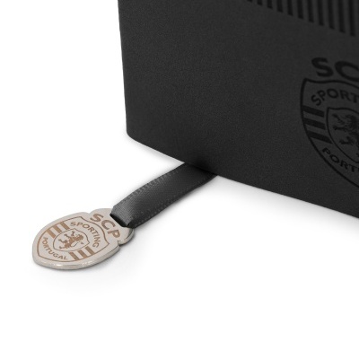 Objeto preto com pendente metálico e fita