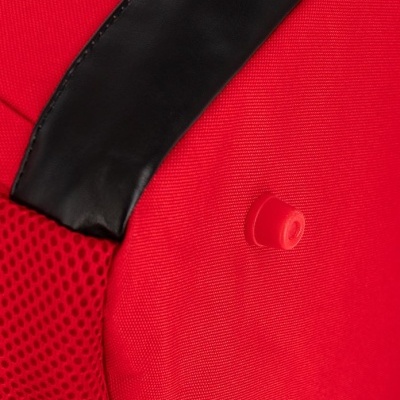 Detalhe de mochila vermelha com alça preta e botão