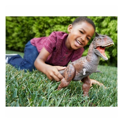 Criança a brincar com brinquedo de dinossauro na relva