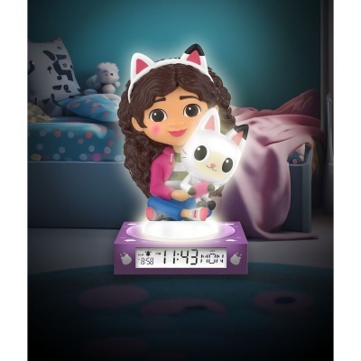 Relógio digital com figura de boneca e gato em mesa num quarto escuro