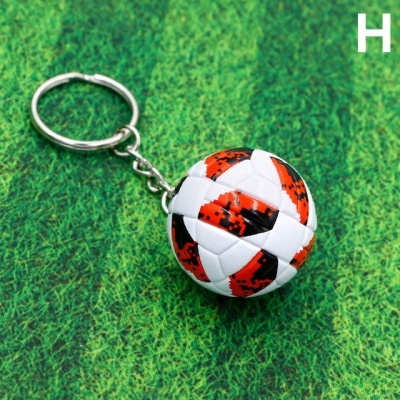 Porta-chaves bola de futebol branco, preto e vermelho em superfície verde