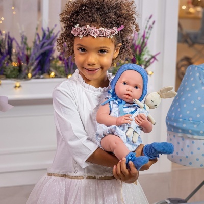 Menina segurando bebé boneca com roupa azul e coelho de peluche