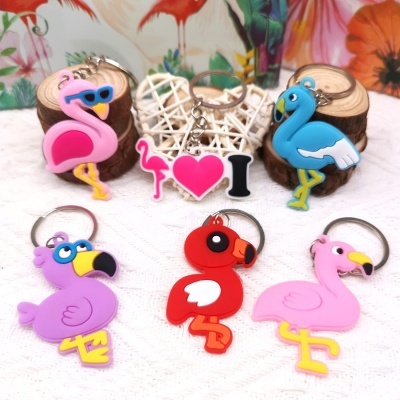 Chaveiros de flamingos coloridos em borracha silicone sobre superfície branca com decoração em fundo