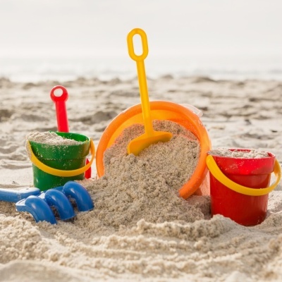 Brinquedos de praia coloridos com baldes e pás na areia junto ao mar