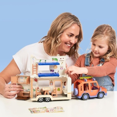 Mulher e criança a brincar com casa de bonecas de madeira e carro de brinquedo