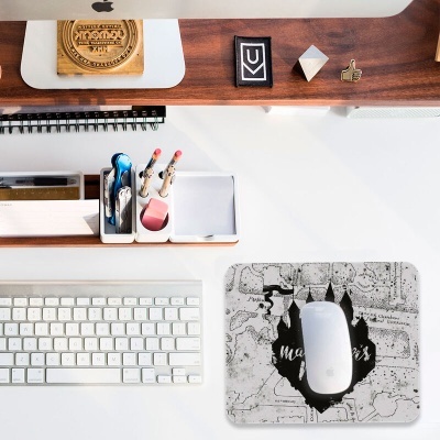 Área de trabalho com teclado branco, rato, tapete de rato com castelos, porta-canetas e monitor Apple